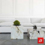 Front interior view of a luxury upholstered minimalist sectional sofa in off white velvet fabric featuring plush cushions and contrasting throw pillows against a white wall paneling background by Bahoo Furniture UAE