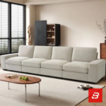 Sunlit interior view of a luxury upholstered linear living room sofa in off white velvet fabric featuring clean modular cushions and a low wooden coffee table by Bahoo Furniture UAE