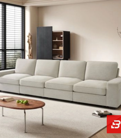 Sunlit interior view of a luxury upholstered linear living room sofa in off white velvet fabric featuring clean modular cushions and a low wooden coffee table by Bahoo Furniture UAE