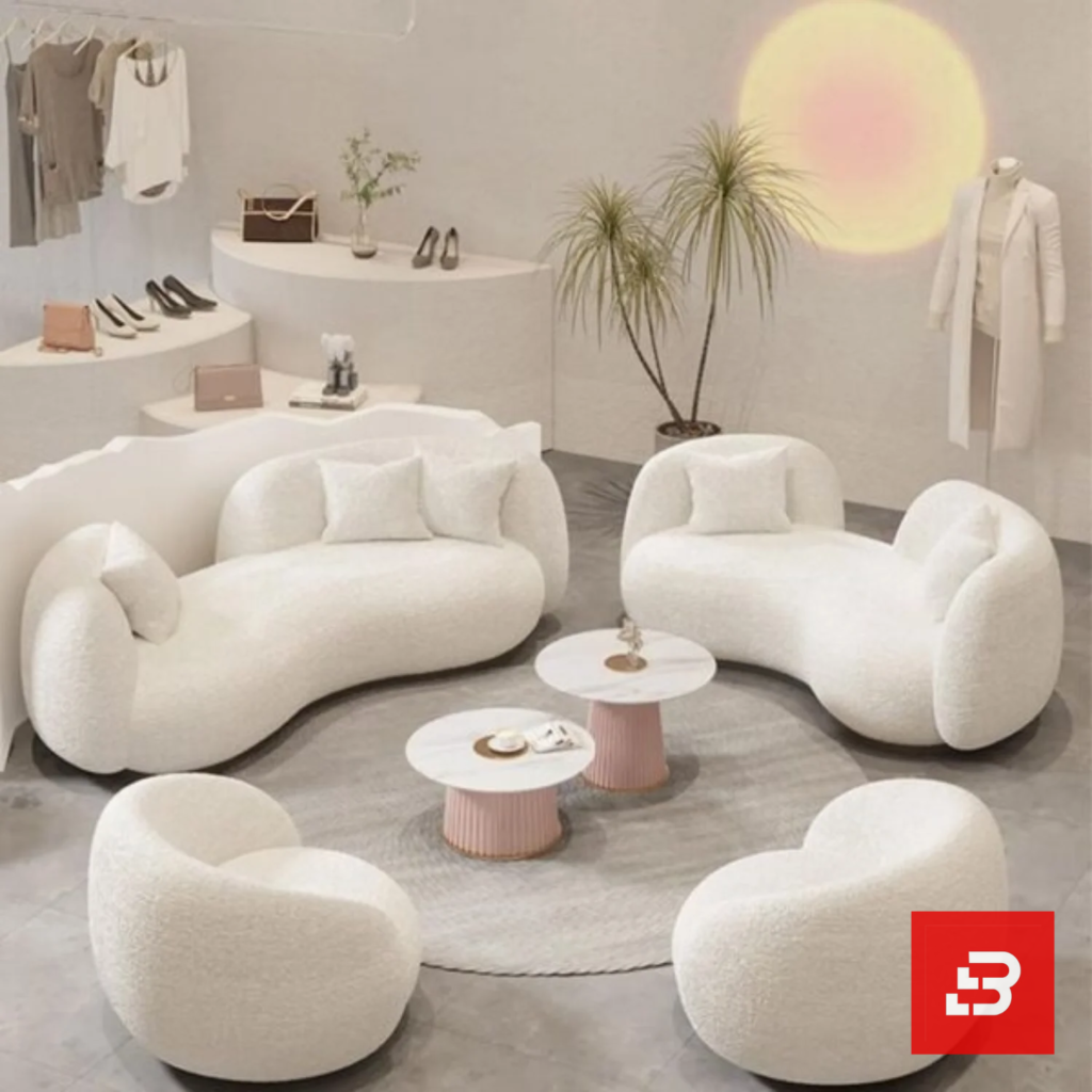 Stylized boutique showroom view of a luxury upholstered organic curved lounge set in off white bouclé fabric featuring matching curved sofas, armchairs, and nested round coffee tables by Bahoo Furniture UAE