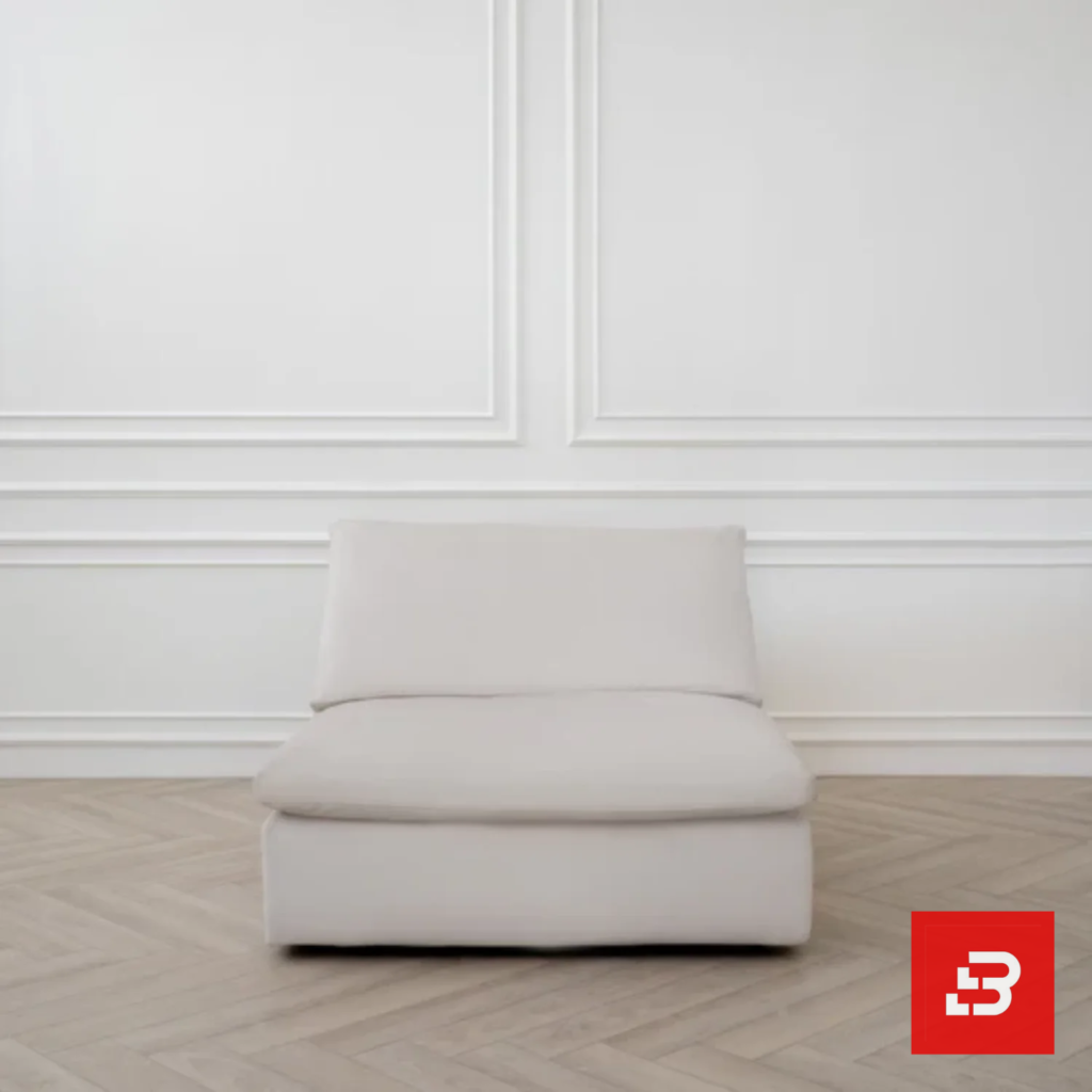 Minimalist studio view of a luxury upholstered modular single armless chair in off white velvet fabric set against a classic white wainscoting wall by Bahoo Furniture UAE