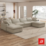 Sunlit interior view of a luxury upholstered modular u-shape sectional sofa in beige velvet fabric featuring dual ottomans and plush modular cushioning in an open-plan living room by Bahoo Furniture UAE