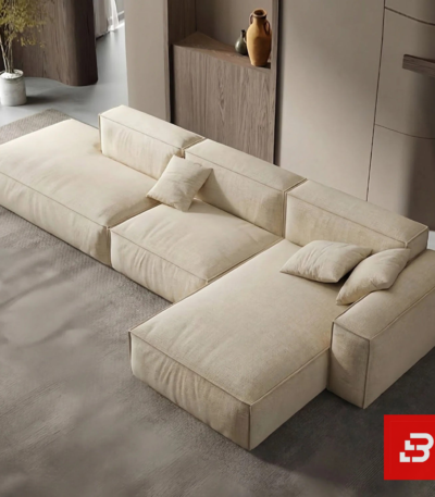 Overhead modern interior view of a luxury upholstered contemporary modular sofa in textured beige fabric featuring an extended chaise lounge and scatter cushions by Bahoo Furniture UAE