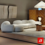 Modern showroom interior view of a luxury upholstered curved modular sofa in textured off white bouclé fabric featuring an organic shape and scatter cushions by Bahoo Furniture UAE