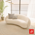 Stunning seaside modern luxury living room interior view of a luxury curved asymmetric sofa upholstered in textured off white bouclé fabric featuring a matching armchair and golden round coffee table by Bahoo Furniture UAE