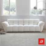 Sunlit minimal modern apartment living room interior view of a luxury channel tufted sofa upholstered in textured off white bouclé fabric featuring structured vertical channel tufting and flared cushioned armrests by Bahoo Furniture UAE