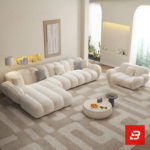 Sunlit minimal modern apartment living room interior view of a luxury channel tufted sectional upholstered in textured off white bouclé fabric featuring a generous chaise lounge and matching barrel armchair by Bahoo Furniture UAE Craftsmanship Details Tactile Comfort: Wrapped in high-density, multi-tonal bouclé that adds rich texture and subtle depth to neutral color schemes while holding up to daily lounging and heavy family use. Supportive Geometry: Every channeled cushion, extended chaise contour, and rounded armrest is padded with high-resilience foam, removing sharp angles to create a secure, comfortable, and inviting environment for relaxed evenings and effortless hosting. Low-Profile Proportions: Designed with structured low-profile silhouettes and continuous clean lines, encouraging an open, airy feeling while maintaining a commanding, sophisticated presence in the room. Sectional Fluidity: Engineered with an expansive extended chaise layout, allowing you to establish a tailored configuration that perfectly fits upscale UAE living room dimensions and open-concept floor plans. Specifications Brand: Bahoo Furniture Model: The Luxury Channel Tufted Sectional Fabric Grade: Luxury Commercial-Grade Bouclé (Off White - #F8F9FA) Internal Structure: Kiln-Dried Hardwood Frame with Reinforced Joinery Configuration Options: Extended Chaise Sectional and Matching Armchair Setup White-Glove Service: Custom Handcrafted in UAE | Complimentary In-Home Assembly Care & Preservation Routine Maintenance: Vacuum gently on low suction with a soft upholstery brush attachment. Spill Response: Blot immediately with a dry, clean microfiber cloth. Clean gentle spots using warm water and mild fabric shampoo; do not scrub forcefully.