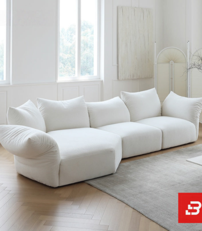 Sunlit minimal modern apartment living room interior view of a luxury cloud sectional upholstered in plush off white bouclé fabric featuring extra-deep lounging cushions and oversized feather-soft scatter pillows by Bahoo Furniture UAE