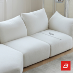 Sunlit minimal modern apartment living room interior view of a luxury cloud sectional upholstered in plush off white bouclé fabric featuring extra-deep lounging cushions and oversized feather-soft scatter pillows by Bahoo Furniture UAE