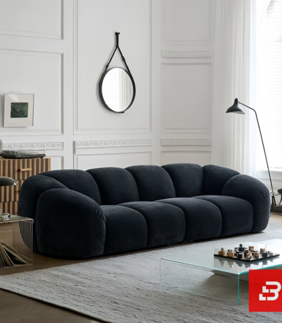 Bright modern minimalist living room interior view of a luxury channel tufted sofa upholstered in textured warm gray bouclé fabric featuring rounded fluted cushions and low-profile armrests by Bahoo Furniture UAE
