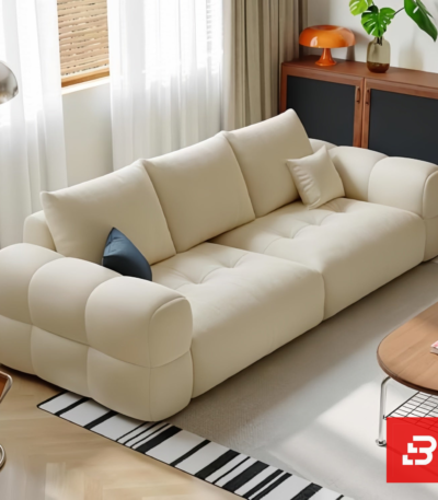 Bright modern living room interior view of a luxury tufted sofa upholstered in textured off white bouclé fabric featuring plush channel-tufted seating cushions and clean modern lines by Bahoo Furniture UAE