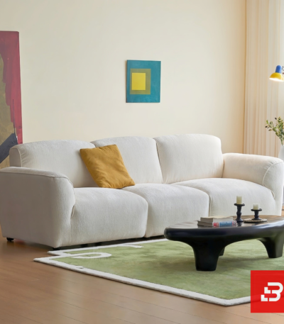 Bright minimalist modern living room interior view of a luxury contemporary modular sofa upholstered in textured off white bouclé fabric featuring clean streamlined armrests and low-profile cushions by Bahoo Furniture UAE