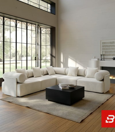 Grand modern luxury living room interior view of a sprawling L-shape sectional sofa upholstered in textured off white bouclé fabric featuring cylindrical bolster pillows and clean low-profile lines by Bahoo Furniture UAE