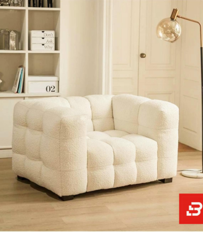 Bright modern cozy living room interior view of a luxury modular armchair upholstered in textured off white bouclé fabric featuring plush channel-tufted square cushioning and low-profile block feet by Bahoo Furniture UAE