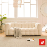 Bright modern cozy living room interior view of a luxury modular armchair upholstered in textured off white bouclé fabric featuring plush channel-tufted square cushioning and low-profile block feet by Bahoo Furniture UAE