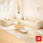 Bright modern cozy living room interior view of a luxury modular armchair upholstered in textured off white bouclé fabric featuring plush channel-tufted square cushioning and low-profile block feet by Bahoo Furniture UAE