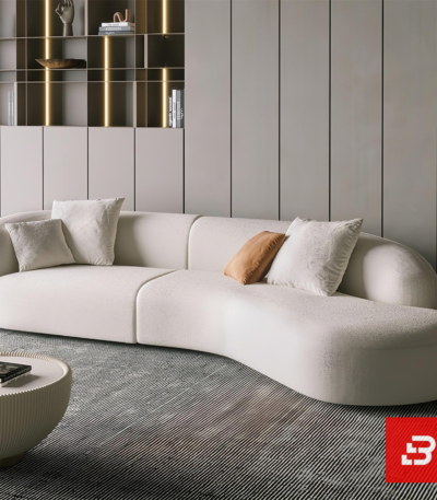 Bright modern luxury living room interior showcasing a curved sofa upholstered in textured off white bouclé fabric featuring an elegant sweeping architectural profile and soft accent cushions by Bahoo Furniture UAE