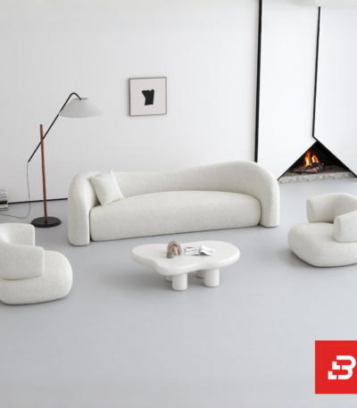 Bright minimalist modern living room interior showcasing a luxury wave sofa upholstered in textured off white bouclé fabric featuring a flowing organic silhouette and matching accent chairs by Bahoo Furniture UAE