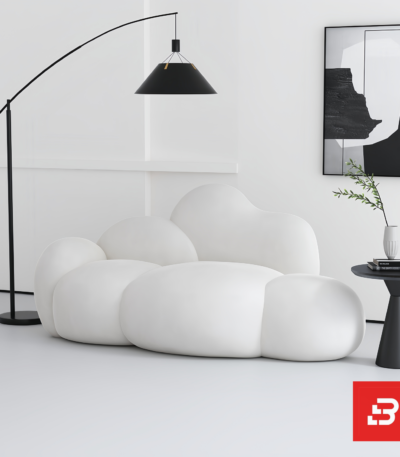Bright minimalist modern living room interior showcasing a luxury cloud lounge chair upholstered in textured off white bouclé fabric featuring organic bulbous modules and a sleek arched floor lamp by Bahoo Furniture UAE