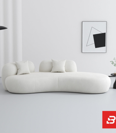 Bright minimalist modern living room interior showcasing an asymmetric chaise sofa upholstered in textured off white bouclé fabric featuring fluid organic curves and matching scatter cushions by Bahoo Furniture UAE