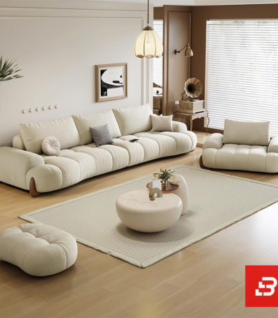 Bright warm modern living room interior showcasing a luxury plissé sectional sofa set upholstered in textured beige bouclé fabric featuring horizontal channel tufting and wooden feet accents by Bahoo Furniture UAEBright warm modern living room interior showcasing a luxury plissé sectional sofa set upholstered in textured beige bouclé fabric featuring horizontal channel tufting and wooden feet accents by Bahoo Furniture UAE