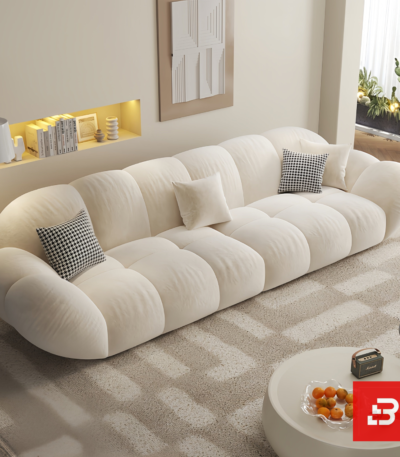Bright warm modern living room interior showcasing a luxury cloud sectional sofa upholstered in textured off white bouclé fabric featuring pillowy channel modules and chic houndstooth accent pillows by Bahoo Furniture UAE