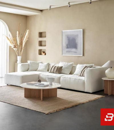 Bright modern living room interior showcasing a luxury modular sectional sofa upholstered in textured off white bouclé fabric featuring a comfortable chaise lounge and neutral decorative pillows by Bahoo Furniture UAE