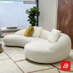 Modern interior view of a luxury organic curved sofa upholstered in textured off white bouclé fabric featuring fluid rounded contours and accent pillows by Bahoo Furniture UAE