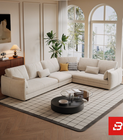 Spacious bright living room interior view of a luxury l-shaped sectional sofa upholstered in textured beige fabric featuring corner configurations and accent cushions by Bahoo Furniture UAE