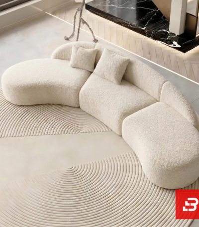 Overhead high-angle interior view of a luxury curved sectional sofa upholstered in textured off white bouclé fabric featuring an organic curved silhouette and scatter cushions by Bahoo Furniture UAE