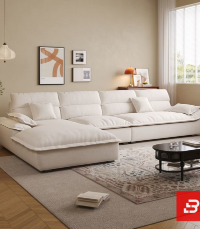 Sunlit luxury living room interior view of a luxury plush cushion sofa upholstered in soft off white fabric featuring deep channeled cushions and matching throw pillows by Bahoo Furniture UAE