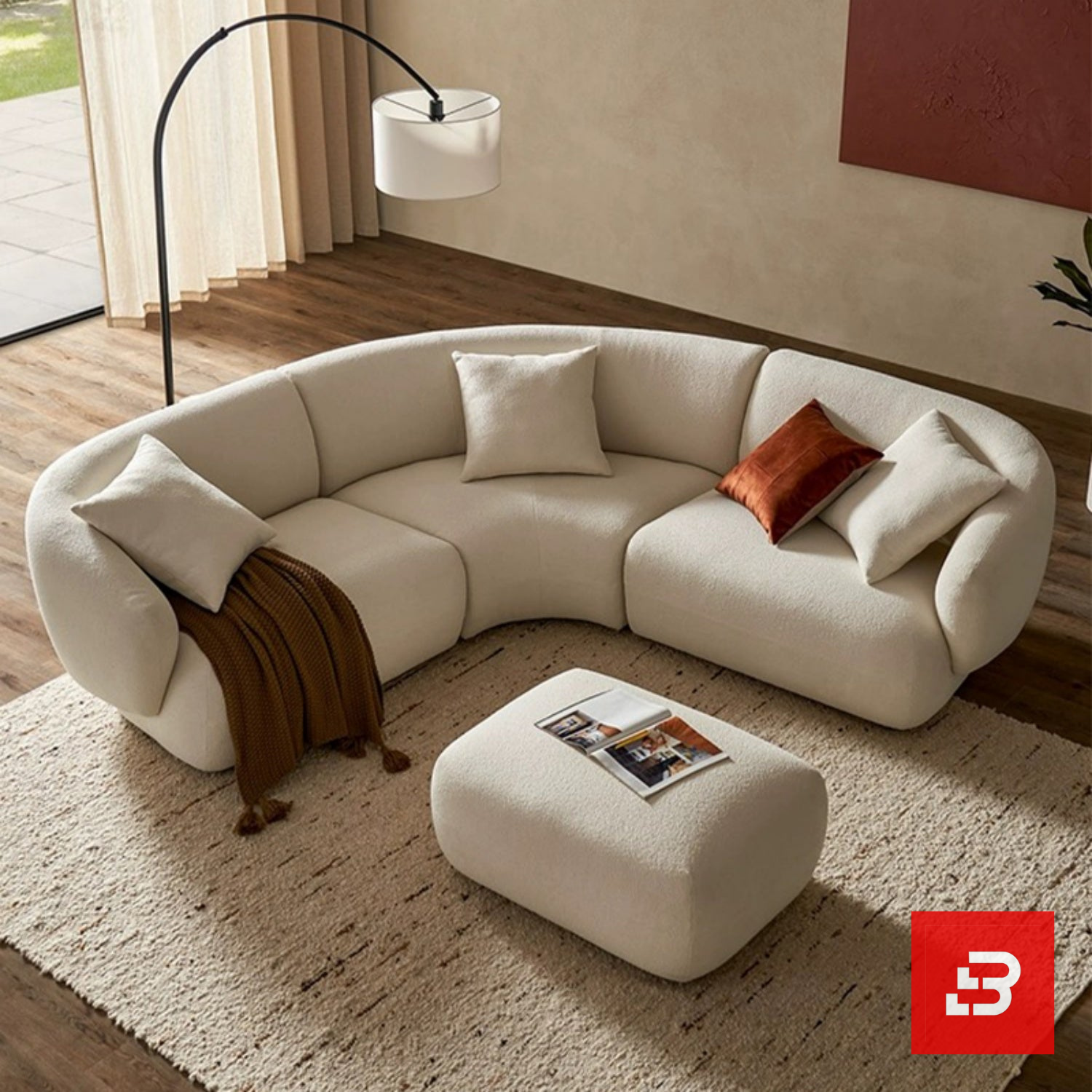 Bahoo Luxury Curved Sofa Upholstered - Bahoo Furniture Sunlit luxury living room interior view of a luxury curved sofa upholstered in textured off white bouclé fabric featuring matching ottoman and rust accent cushions by Bahoo Furniture UAE