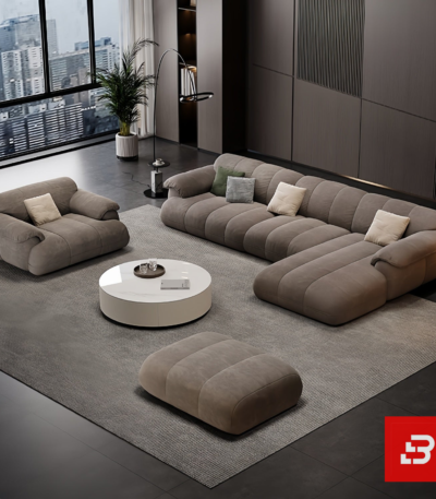 Sleek modern penthouse living room interior view of a luxury channel tufted sectional sofa upholstered in textured warm gray fabric featuring matching armchair and ottoman by Bahoo Furniture UAE