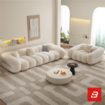 Bright warm living room interior view of a luxury ribbed modular sofa upholstered in textured off white bouclé fabric featuring distinct vertical channeled rolls and accent cushions by Bahoo Furniture UAE
