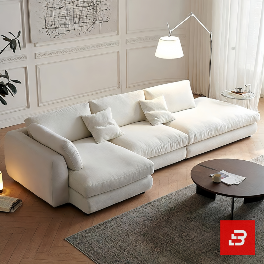 Modern bright living room interior view of a luxury modern sectional sofa upholstered in textured off white bouclé fabric featuring a plush chaise lounge and scatter cushions by Bahoo Furniture UAE