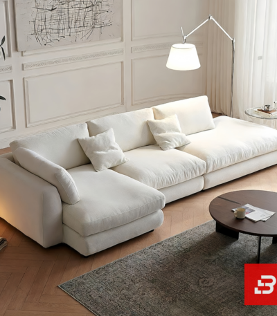 Modern bright living room interior view of a luxury modern sectional sofa upholstered in textured off white bouclé fabric featuring a plush chaise lounge and scatter cushions by Bahoo Furniture UAE