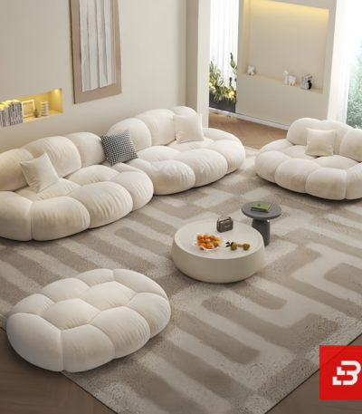Bright minimalist modern living room interior view of a luxury cloud modular sofa set upholstered in textured off white bouclé fabric featuring independent modules, an armchair, and a matching ottoman by Bahoo Furniture UAE