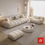 Bright modern sunlit living room interior view of a luxury channel modular lounge set upholstered in textured off white bouclé fabric featuring horizontal ribbed modules, an armchair, and an ottoman by Bahoo Furniture UAE
