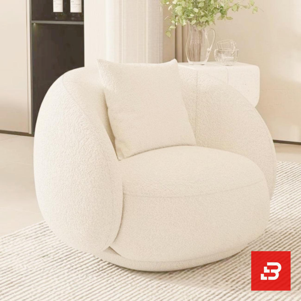Sunlit minimalist modern apartment living room interior view of a luxury swivel barrel armchair upholstered in textured off white bouclé fabric featuring a matching accent pillow by Bahoo Furniture UAE