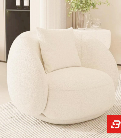 Sunlit minimalist modern apartment living room interior view of a luxury swivel barrel armchair upholstered in textured off white bouclé fabric featuring a matching accent pillow by Bahoo Furniture UAE
