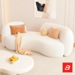 Sunlit minimalist modern apartment living room interior view of a luxury swivel barrel armchair upholstered in textured off white bouclé fabric featuring a matching accent pillow by Bahoo Furniture UAE