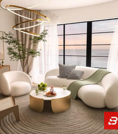 Stunning seaside modern luxury living room interior view of a luxury curved asymmetric sofa upholstered in textured off white bouclé fabric featuring a matching armchair and golden round coffee table by Bahoo Furniture UAE