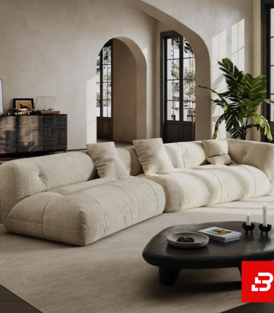 Sunlit architectural luxury living room interior showcasing a low-profile modular sofa upholstered in textured beige bouclé fabric featuring deep tufted seats and neutral accent pillows by Bahoo Furniture UAE