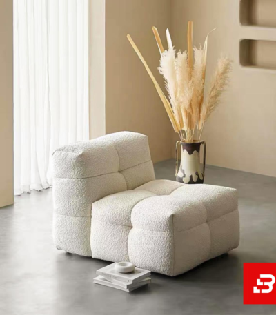 Warm minimalist living room interior showcasing a luxury modular armchair upholstered in soft off white bouclé fabric featuring tufted block cushioning and stackable books underneath by Bahoo Furniture UAE