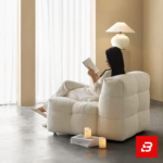 Warm minimalist living room interior showcasing a luxury modular armchair upholstered in soft off white bouclé fabric featuring tufted block cushioning and stackable books underneath by Bahoo Furniture UAE