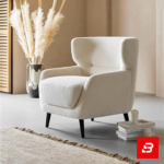 Warm minimalist living room interior showcasing a luxury wingback armchair upholstered in soft off white bouclé fabric featuring supportive flared wings and dark wooden legs by Bahoo Furniture UAE