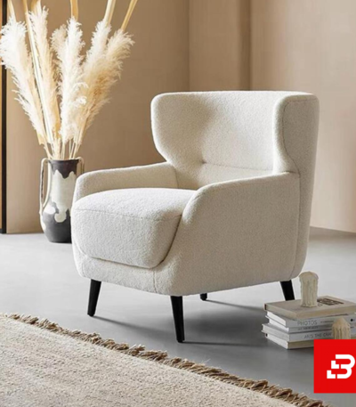 Warm minimalist living room interior showcasing a luxury wingback armchair upholstered in soft off white bouclé fabric featuring supportive flared wings and dark wooden legs by Bahoo Furniture UAE
