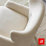 Warm minimalist living room interior showcasing a luxury wingback armchair upholstered in soft off white bouclé fabric featuring supportive flared wings and dark wooden legs by Bahoo Furniture UAE
