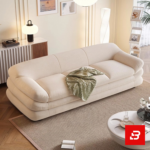 Warm sunlit modern minimalist living room interior showcasing a luxury layered sofa upholstered in textured off white bouclé fabric featuring distinctive multi-tiered horizontal cushioning and soft throw blanket by Bahoo Furniture UAE