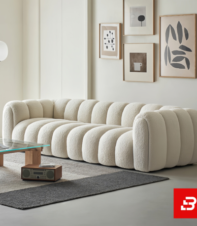 Sunlit modern minimalist living room interior showcasing a luxury ribbed sofa upholstered in textured off white bouclé fabric featuring distinct vertical channel tufting and continuous curved lines by Bahoo Furniture UAE